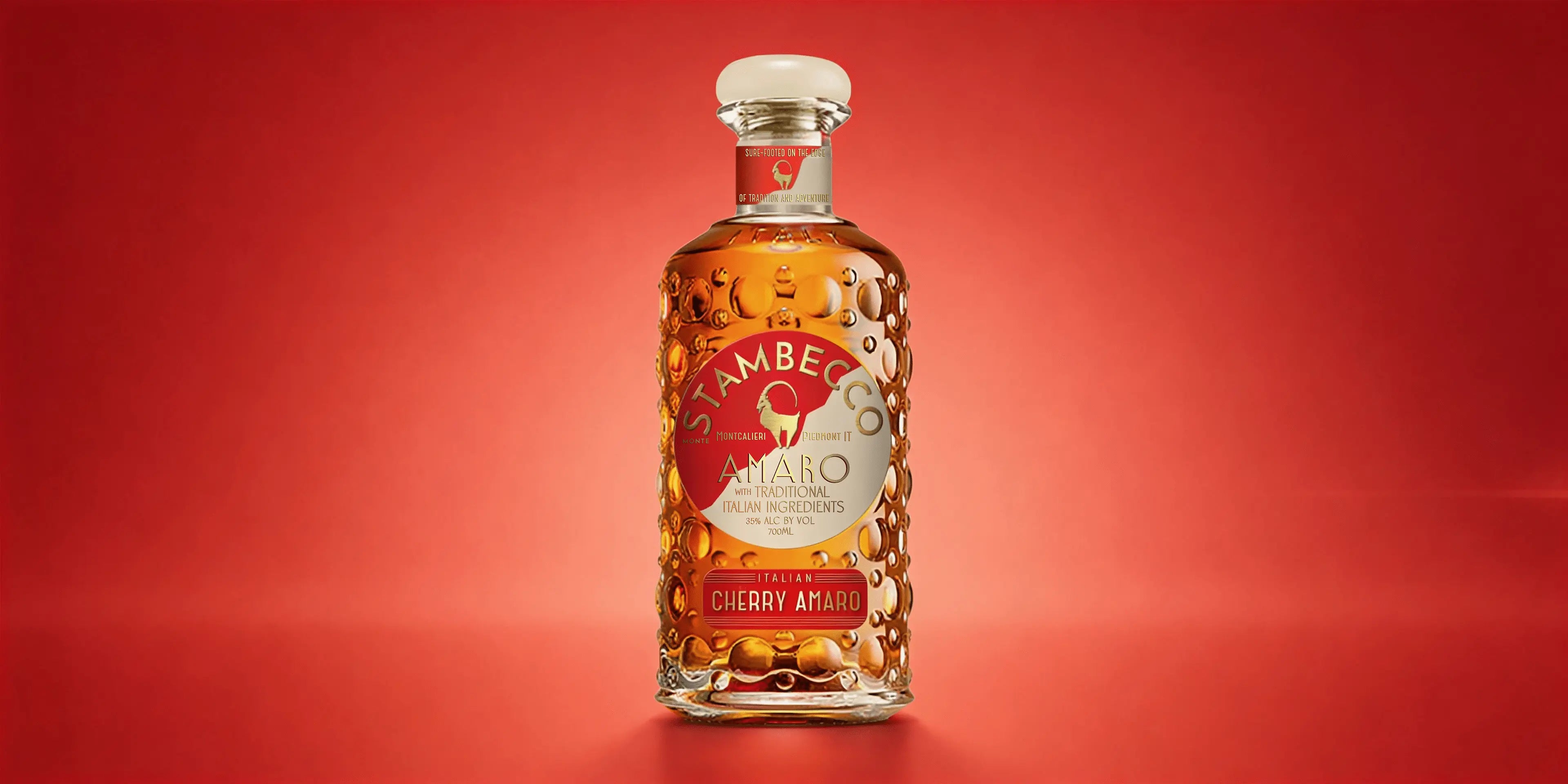 A bottle of Stambecco Cherry Amaro on a red background