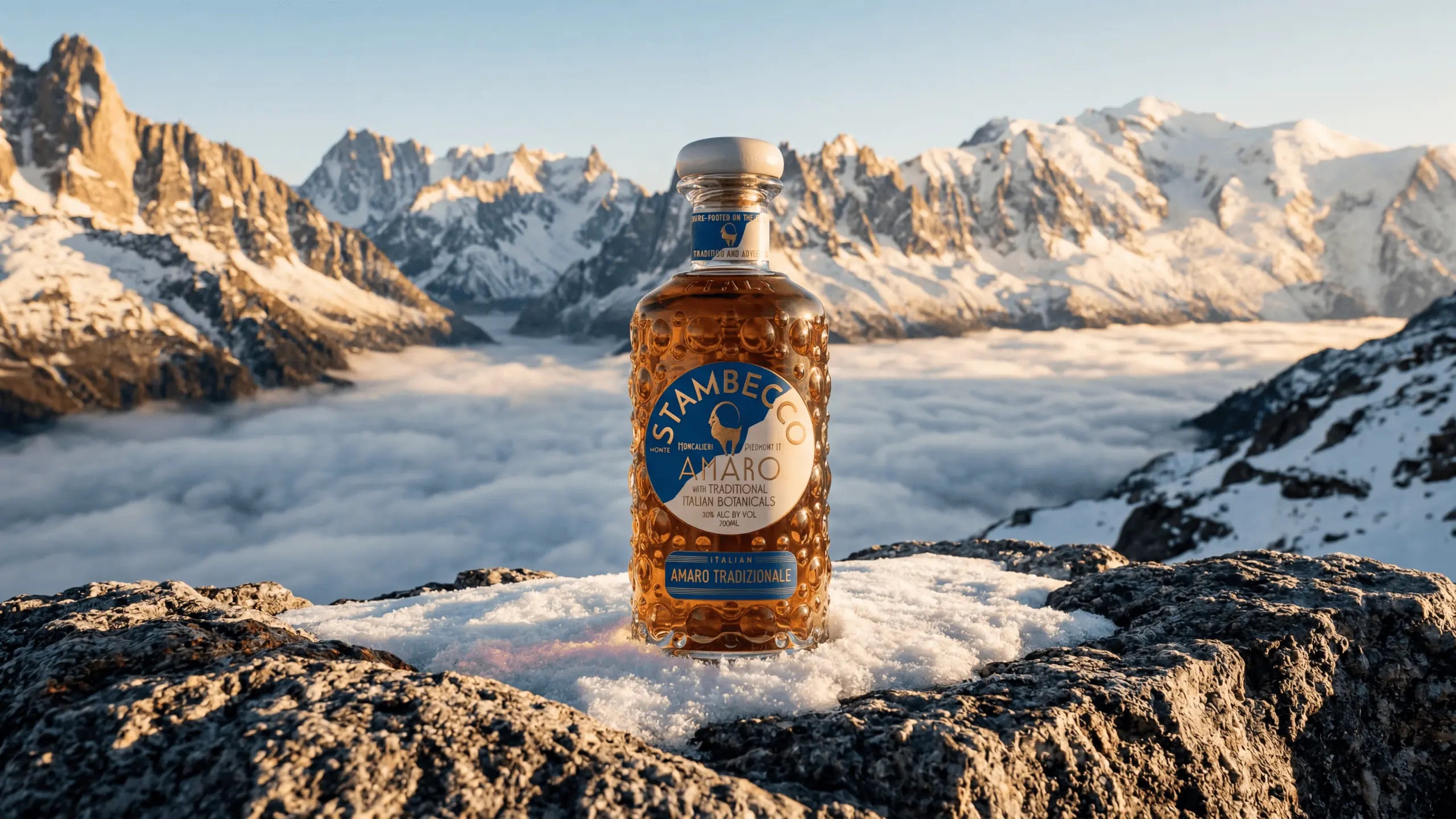 A bottle of Stambecco Amaro on a mountain peak with clouds below